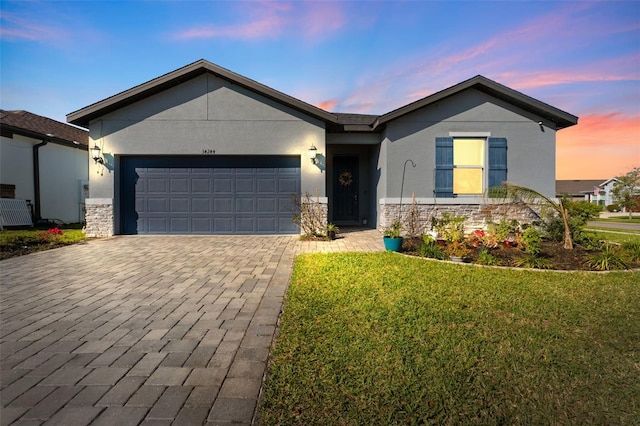 ranch-style house featuring an attached garage, stone siding, and stucco siding