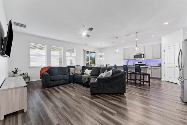 living room with visible vents, baseboards, recessed lighting, ceiling fan with notable chandelier, and dark wood-style floors