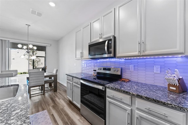 kitchen featuring tasteful backsplash, visible vents, dark stone countertops, appliances with stainless steel finishes, and dark wood-style floors