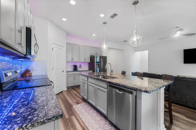 kitchen with a breakfast bar area, dark wood finished floors, a sink, stainless steel appliances, and open floor plan