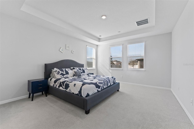 bedroom featuring a tray ceiling, baseboards, visible vents, and carpet floors