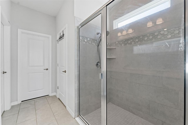 full bath featuring tile patterned floors, baseboards, and a shower stall