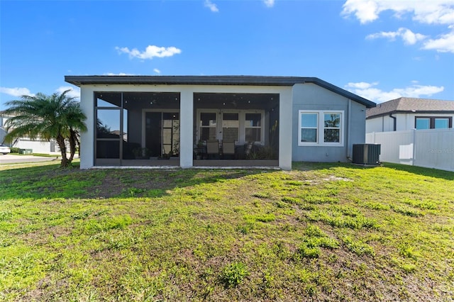 rear view of property with central air condition unit, fence, a lawn, and a sunroom