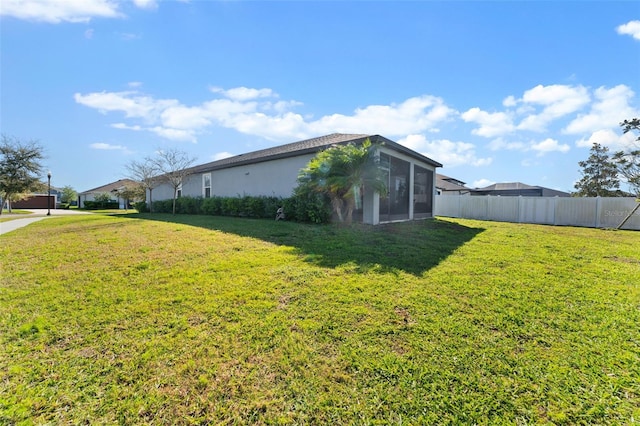 view of property exterior featuring stucco siding, a lawn, a sunroom, and fence