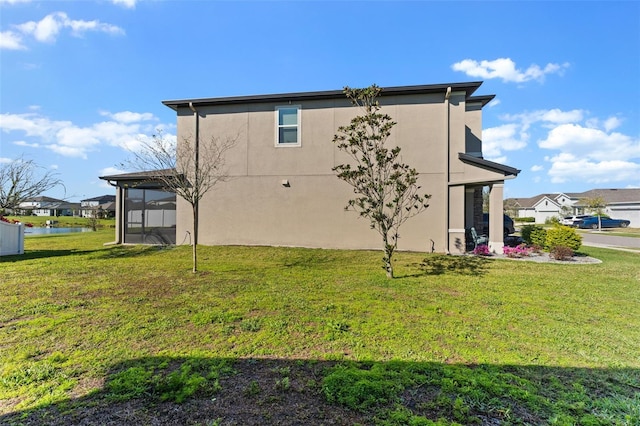 view of property exterior with stucco siding, a yard, and a sunroom