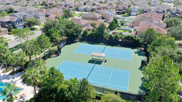 view of tennis court with a residential view and fence