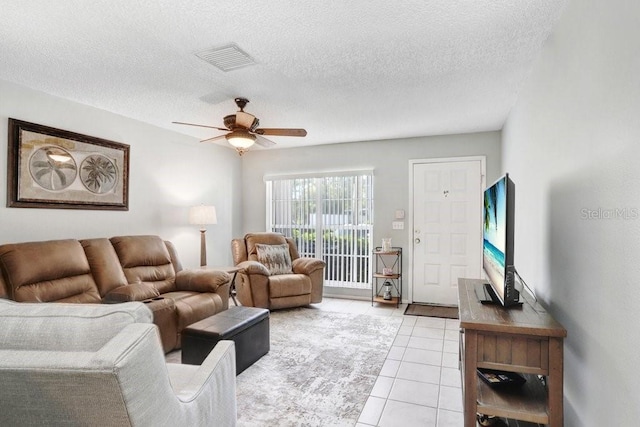 living room with light tile patterned floors, visible vents, a textured ceiling, and a ceiling fan