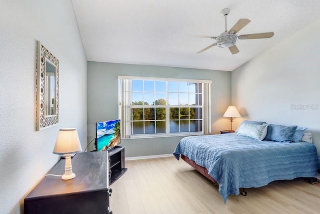 bedroom with baseboards, ceiling fan, vaulted ceiling, wood finished floors, and a textured ceiling