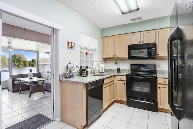 kitchen with a sink, black appliances, visible vents, and light brown cabinetry