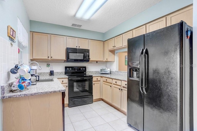 kitchen featuring black appliances, light brown cabinets, visible vents, and a sink