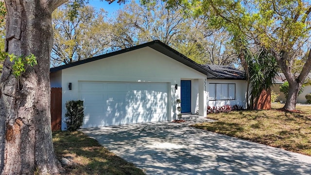 single story home featuring a garage, a front yard, driveway, and stucco siding