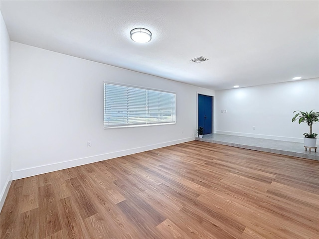 empty room featuring visible vents, light wood-style flooring, and baseboards