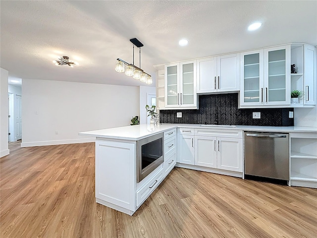 kitchen featuring a peninsula, light wood finished floors, and appliances with stainless steel finishes