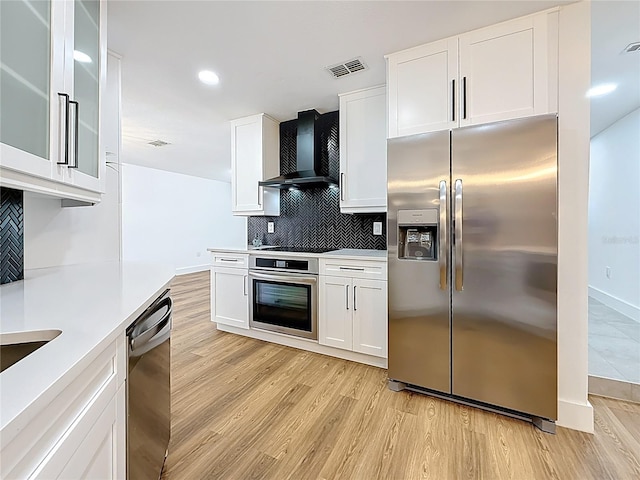 kitchen featuring visible vents, decorative backsplash, light countertops, appliances with stainless steel finishes, and wall chimney range hood