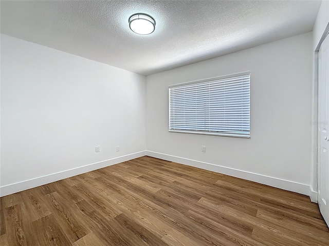 empty room featuring baseboards, a textured ceiling, and wood finished floors