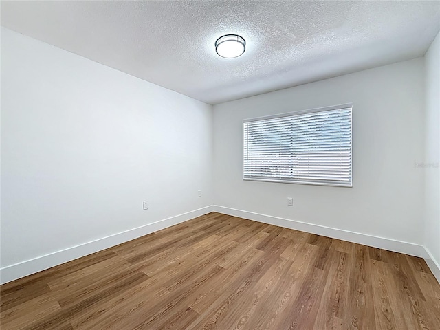 unfurnished room featuring baseboards, a textured ceiling, and wood finished floors