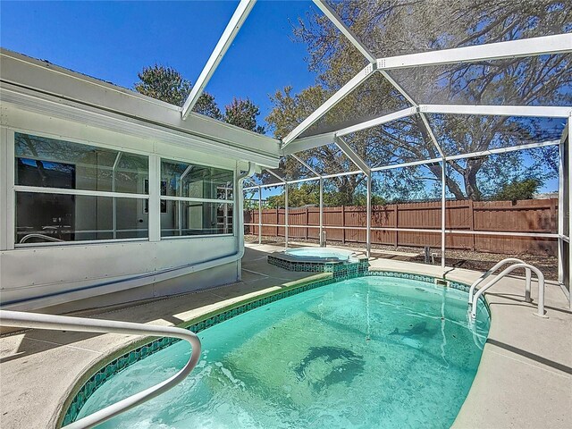 view of pool with glass enclosure, a patio, a fenced backyard, and a pool with connected hot tub