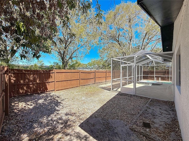 view of yard featuring glass enclosure, a patio area, and a fenced backyard