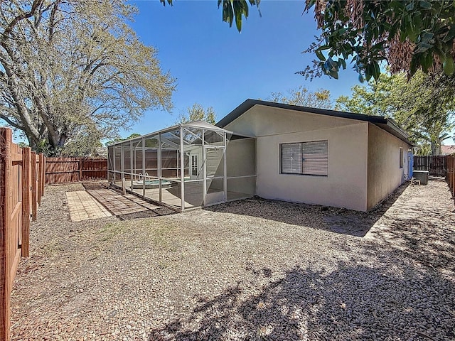 back of house featuring a lanai, a swimming pool, stucco siding, a fenced backyard, and a patio area