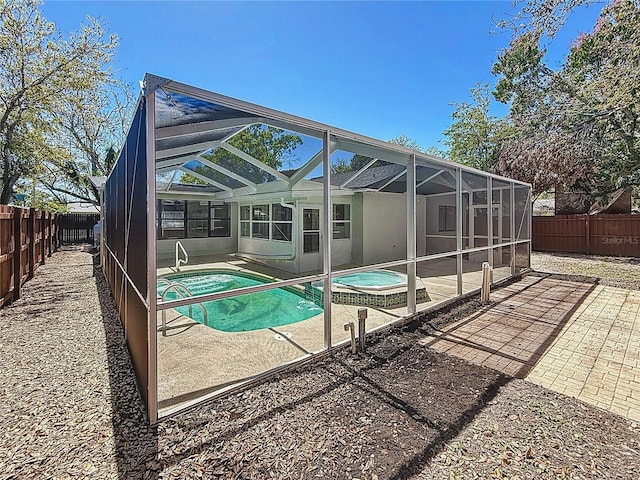 view of swimming pool featuring a patio area, a fenced backyard, a pool with connected hot tub, and a lanai