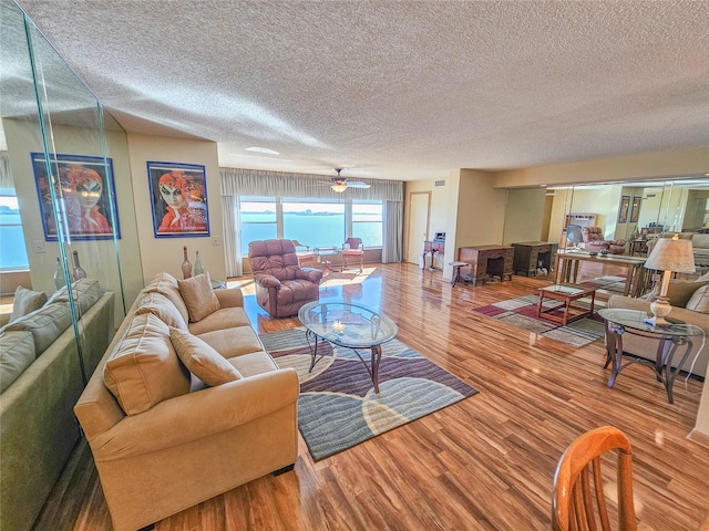 living room featuring a textured ceiling, wood finished floors, and a ceiling fan