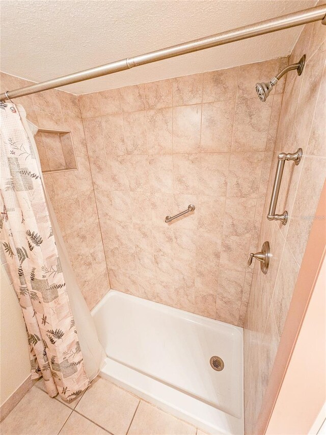 full bath featuring tile patterned flooring, curtained shower, and a textured ceiling