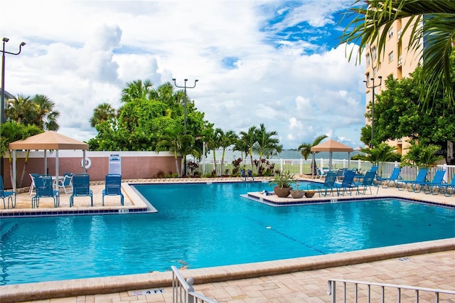 community pool with a patio area and fence