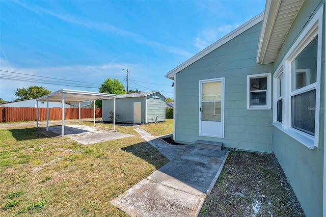 view of yard featuring a patio, a detached carport, an outdoor structure, and fence