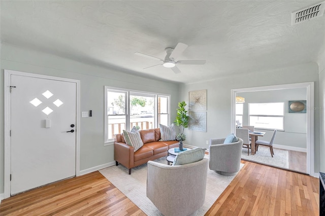 living room with visible vents, a healthy amount of sunlight, light wood-type flooring, and baseboards