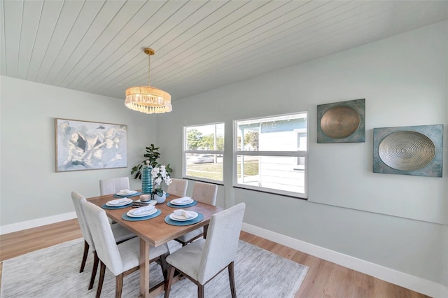 dining room featuring a chandelier, baseboards, and wood finished floors