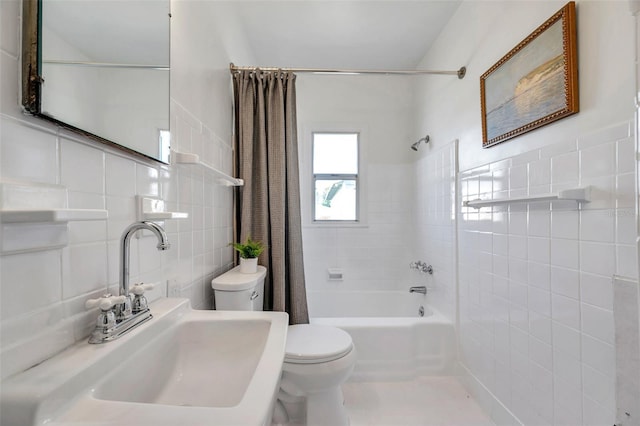 bathroom featuring a sink, shower / bath combo with shower curtain, toilet, and tile walls