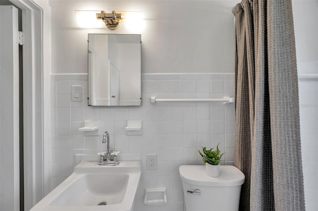 bathroom featuring tile walls, toilet, and a sink