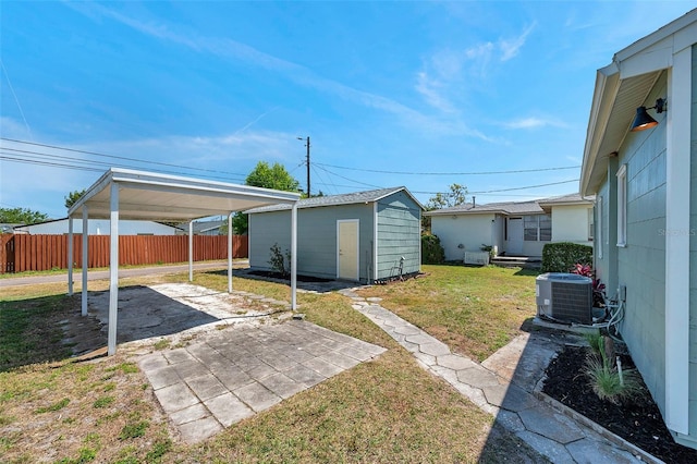 view of yard with an outdoor structure, fence, driveway, and central AC