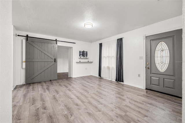 entryway featuring baseboards, a textured ceiling, a barn door, and wood finished floors