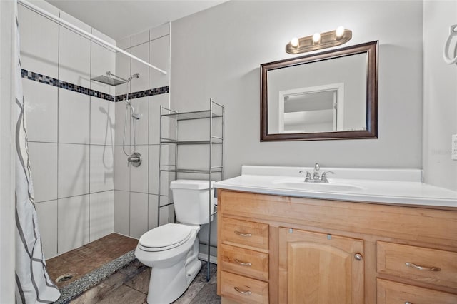 bathroom featuring vanity, toilet, and a tile shower