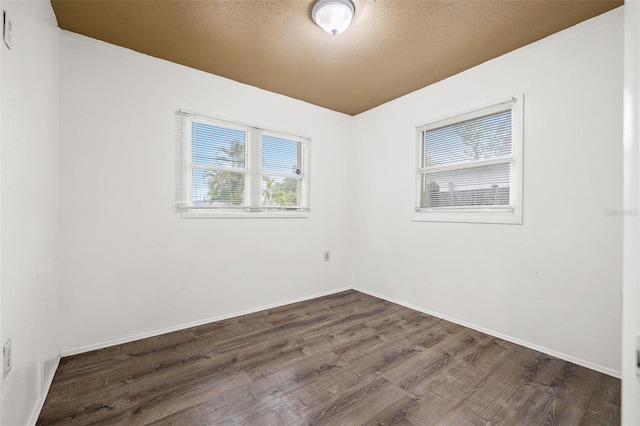 spare room featuring a textured ceiling, baseboards, and wood finished floors