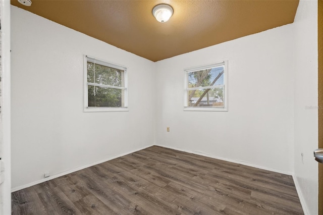 spare room featuring baseboards and dark wood-style flooring