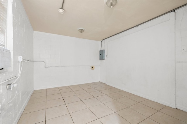 empty room featuring concrete block wall and electric panel