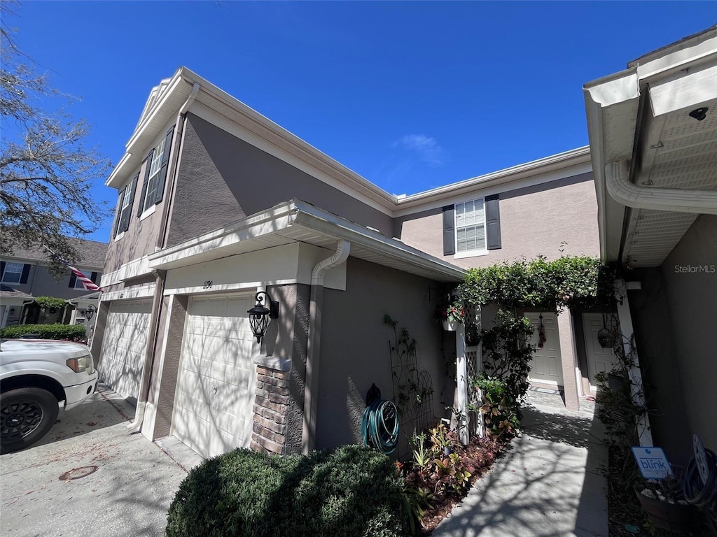 view of side of property with an attached garage, driveway, and stucco siding