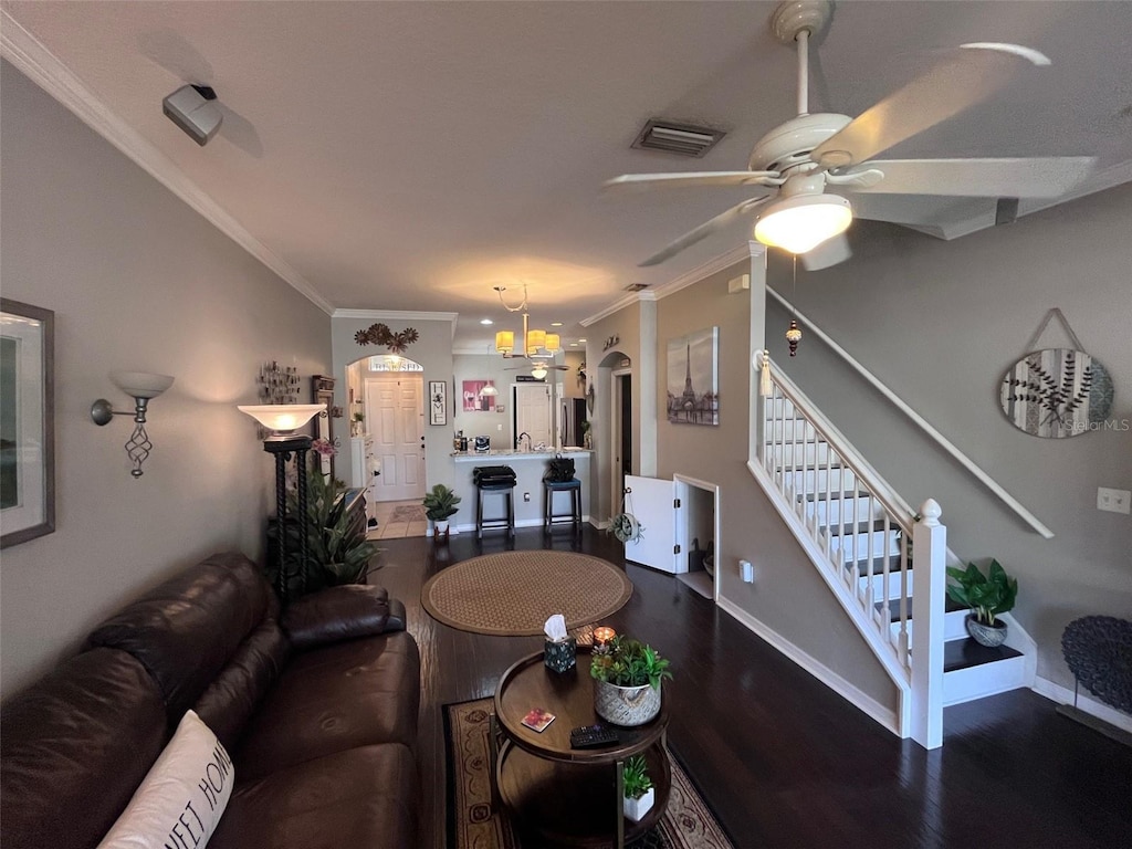 living area featuring visible vents, wood finished floors, ornamental molding, and a ceiling fan