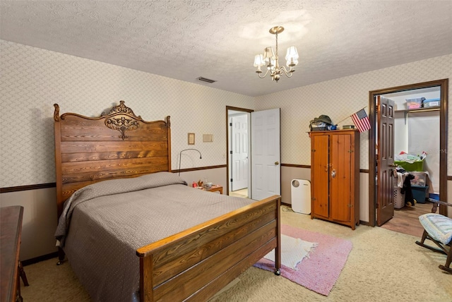 bedroom featuring visible vents, wallpapered walls, a chandelier, light carpet, and a textured ceiling