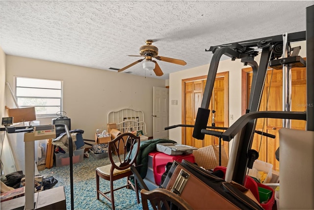 exercise area with a textured ceiling and ceiling fan