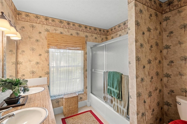 full bathroom with toilet, shower / bath combination with glass door, wallpapered walls, and a sink