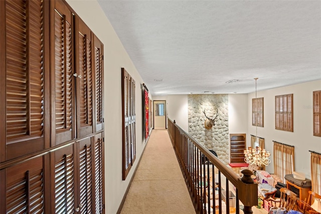 hallway featuring light colored carpet and a textured ceiling