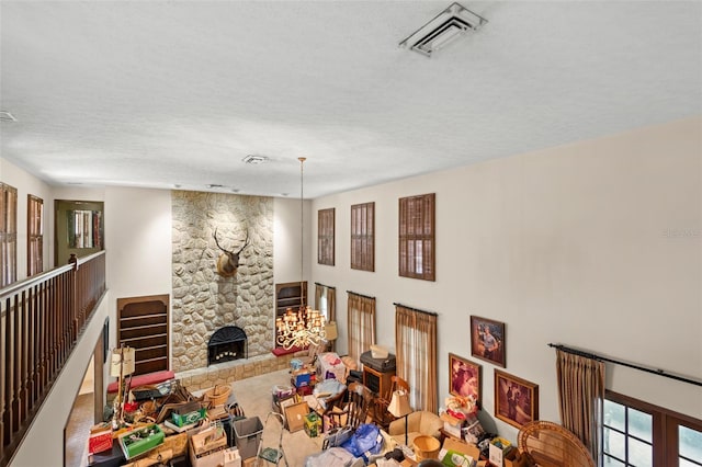 living area featuring a stone fireplace, visible vents, and a textured ceiling