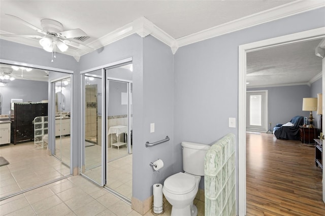 ensuite bathroom with a ceiling fan, ornamental molding, a shower stall, toilet, and connected bathroom