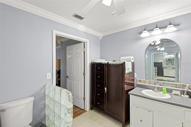 bathroom featuring vanity, visible vents, ceiling fan, ornamental molding, and toilet