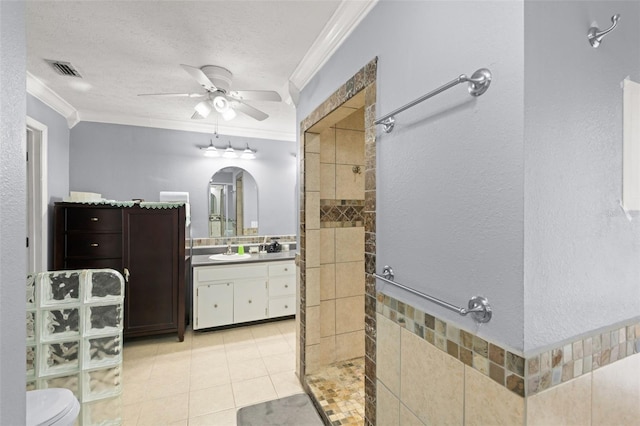 full bath with a textured ceiling, crown molding, vanity, and tiled shower