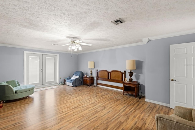 sitting room with visible vents, light wood-style flooring, french doors, and ornamental molding