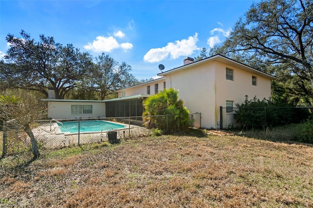 back of property featuring fence, a fenced in pool, a sunroom, stucco siding, and a chimney